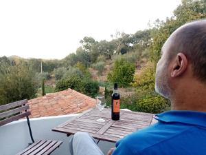Ein Mann, der mit einer Flasche Wein am Tisch sitzt. in der Unterkunft TerraFazBem in Marvão