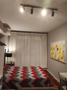 a bedroom with a bed with a red and white blanket at Studioaconchegantepoa in Porto Alegre