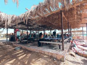 a group of people sitting on benches under a straw roof at Sayadeen Village - Red Sea Riviera in Nuweiba