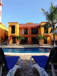 dwa krzesła i basen przed budynkiem w obiekcie Hacienda Valentina w mieście Playa del Carmen
