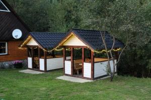 a gazebo with a black roof in a yard at Відпочинковий комплекс "Alpha Plus" in Yablunytsya