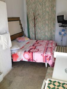 a small bedroom with a bed with a pink comforter at Hôtel Sindbad in Houmt Souk