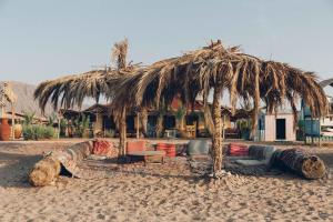 a straw hut with couches and a table on the beach at Sayadeen Village - Red Sea Riviera in Nuweiba
