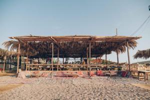 a straw hut on the beach with tables and chairs at Sayadeen Village - Red Sea Riviera in Nuweiba