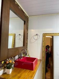 a person taking a picture of a red sink in a bathroom at Chale Sabrina in Campos do Jordão