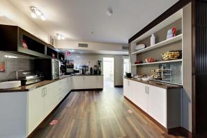 a large kitchen with white cabinets and wooden floors at Best Western Plus Osoyoos Hotel & Suites in Osoyoos