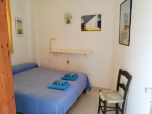 Un pequeño dormitorio con una cama azul y una silla en Apartments Pepe, Es Pujols-Formentera vacaciones, en Es Pujols