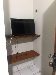 a television sitting on a shelf in a room at Pousadinha- Melhor Localização in Porto Seguro