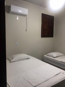 a bedroom with two beds and a air conditioner at Pousadinha- Melhor Localização in Porto Seguro