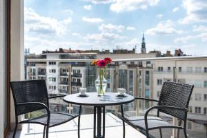 stół z 2 krzesłami oraz waza z kwiatami na balkonie w obiekcie Park Inn by Radisson Poznan w Poznaniu