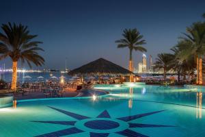 a swimming pool with a pool table and chairs at Radisson Blu Hotel & Resort, Abu Dhabi Corniche in Abu Dhabi