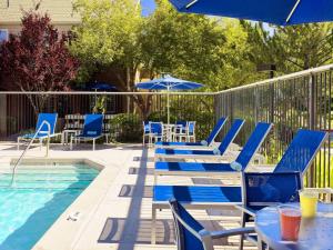 a swimming pool with blue chairs and a table and umbrella at Sonesta ES Suites Columbus Dublin in Dublin