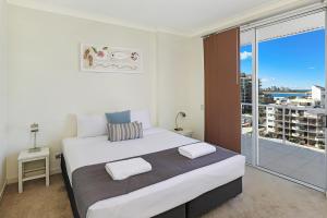una camera da letto con un grande letto bianco e un balcone di Pandanus Mooloolaba a Mooloolaba