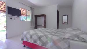 a white bedroom with a bed and a television at Chalés Pirauá in São Miguel dos Milagres