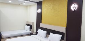 a room with two beds and a yellow wall at Hotel Teeja's - Haldi Restaurant Aiims road Jodhpur in Jodhpur +31 photos