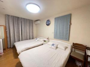 Habitación de hotel con 2 camas y reloj en la pared en MIKOTO HOUSE, en Kashū