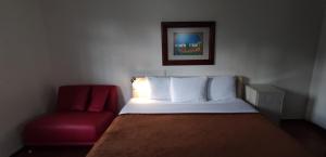 - une chambre avec un lit et une chaise rouge dans l'établissement Hostal de Las Américas, à Oaxaca