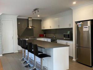 una cocina con una isla con taburetes y nevera en Melandy Main House, en Inverloch