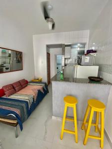 1 dormitorio con 1 cama y 2 taburetes amarillos en Studio Copacabana, en Río de Janeiro