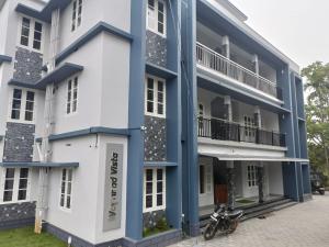 un bâtiment bleu et blanc avec une moto garée devant dans l'établissement Wayanad Vista Service Apartment, à Wayanad