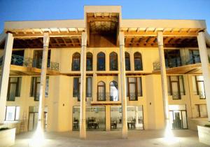 a large yellow building with columns and windows at Grand Ark Bukhara in Bukhara