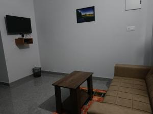 een woonkamer met een bank en een tafel bij Wayanad Vista Service Apartment in Wayanad
