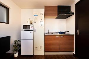 una pequeña cocina con nevera y microondas en Apartment Sunbright, en Tokio