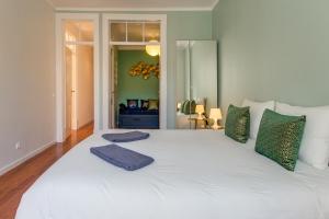 een groot wit bed met groene kussens erop bij Spacious, Bright and Newly Renovated 2 Bedroom Apartment, Lisbon Historical Center, Madragoa in Lissabon