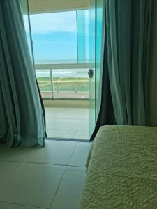 a bedroom with a bed and a window with a view of the ocean at Apartamento Vista Mar – Pé na Areia in Cabo Frio +28 photos
