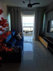 a living room with a blue couch and a television at Apartamento Vista Mar – Pé na Areia in Cabo Frio