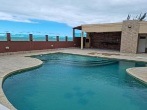a swimming pool with blue water in front of a building at Apartamento Vista Mar – Pé na Areia in Cabo Frio
