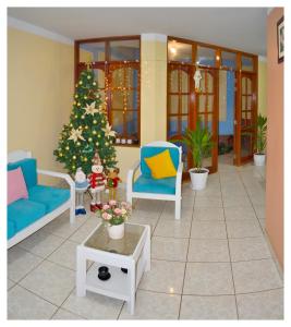 a living room with a christmas tree and blue chairs at Hospedaje La Casa Blanca in Urbanizacion Buenos Aires