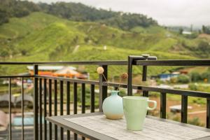 a table with a vase and a cup on a balcony at Gorgeous Sunset & Tea Plantation View-Premium Hotel Bed in Kampung Kuala Terla