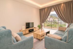 Sala de estar con 2 sillas azules y TV en Gorgeous Sunset & Tea Plantation View-Premium Hotel Bed, en Kampung Kuala Terla
