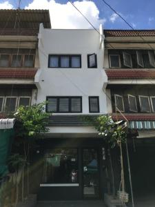 un edificio blanco con ventanas negras encima en เจริญพาณิชย์ รูมส์ en Pathum Thani
