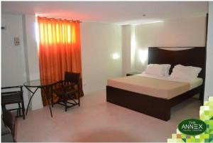 a hotel room with a bed and a table and a desk at Annex Hotel Tavern in Surigao