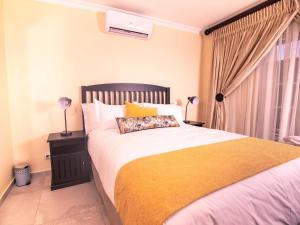 AcornhoekMasingitana Hotel的卧室里有一张大床，床上铺着黄色毯子