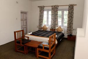 Un dormitorio con una cama y dos sillas y una ventana. en Hotel Ashai, en Srinagar