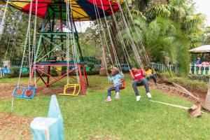een groep kinderen die spelen op schommels in een park bij Olive Green Garden Resort in Nairobi