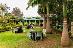 een groep tafels en stoelen in een tuin met palmbomen bij Olive Green Garden Resort in Nairobi