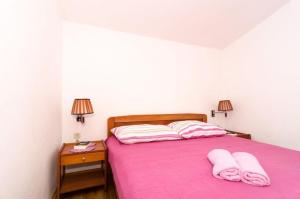 um quarto com uma cama rosa com duas toalhas em Apartments Žuronja em Putniković