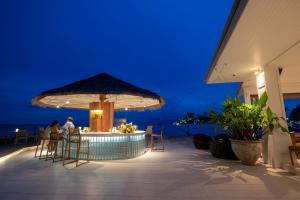 a bar with people sitting at a table with an umbrella at Rocky's Boutique Resort - Veranda Collection Samui in Lamai