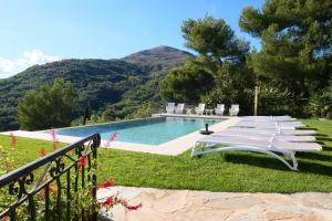 a row of lounge chairs next to a swimming pool at La Bastide des Pins in Vence