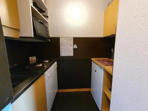 una pequeña cocina con armarios blancos y una pared negra en Appartement La Plagne-Tarentaise, 1 pièce, 4 personnes - FR-1-353-80, en Les Coches