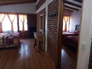 1 dormitorio con 2 camas y pared de ladrillo en Cabañas Los Bosques del Zembo en Huasca de Ocampo