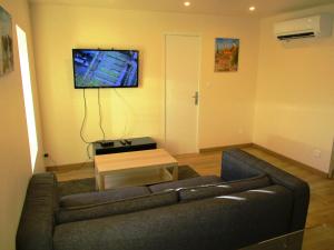 a living room with a couch and a tv on the wall at Le mas des Lilas in Uzès