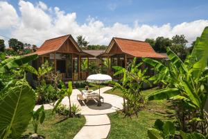 un jardín con una casa con una mesa y una sombrilla en Villa Kamal Umalas, en Kerobokan