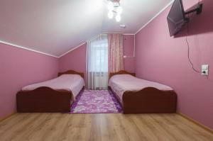 a bedroom with two beds and a pink wall at Hotel Dinastiya in Nizhny Novgorod