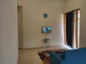 uma sala de estar com um sofá azul e uma televisão na parede em Homestay Zaki D'Gerik em Gerik