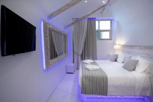 a white bedroom with a bed and a tv at Rhodos Horizon Blu-Adults Only in Rhodes Town